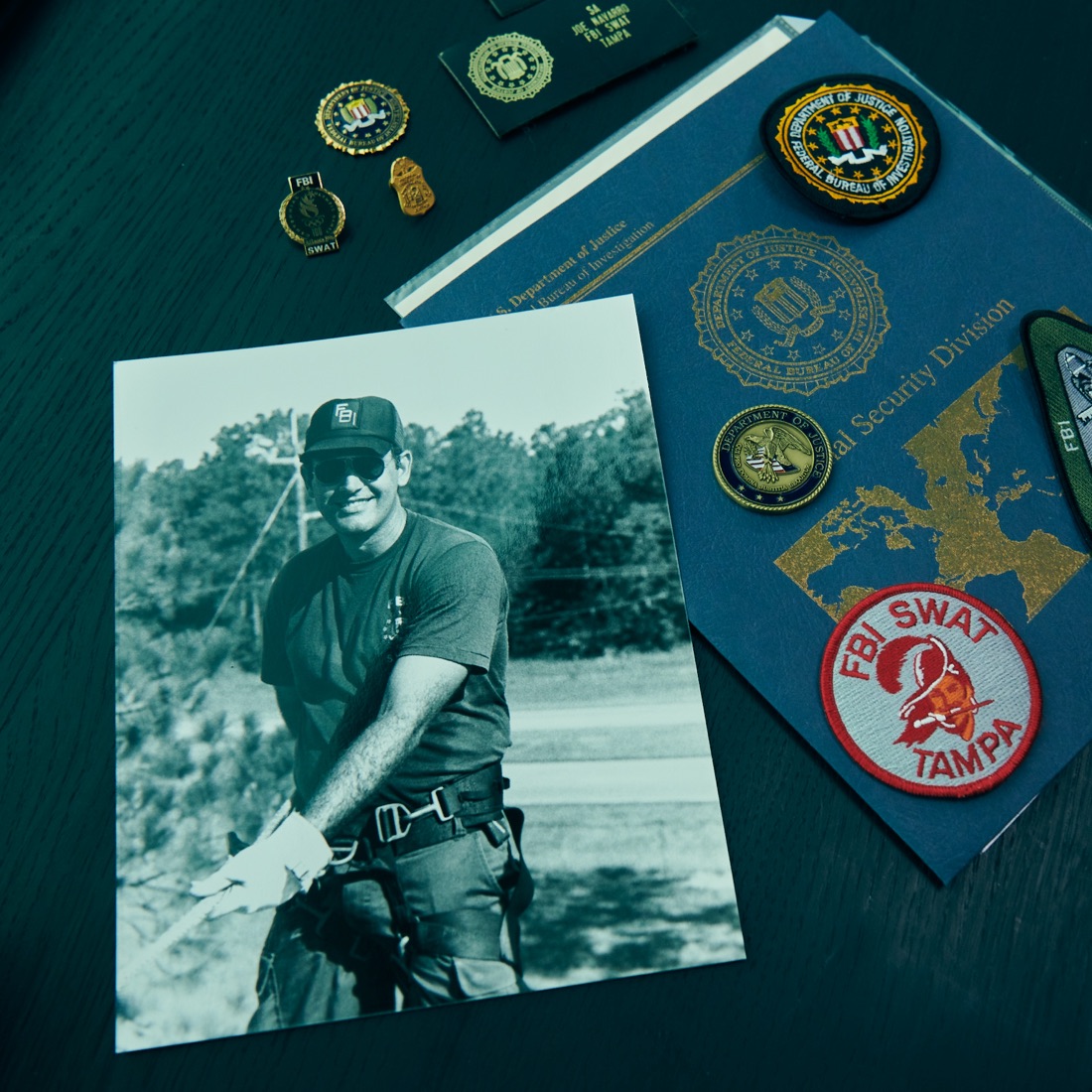 Photo of a man, a folder and different badges on a table